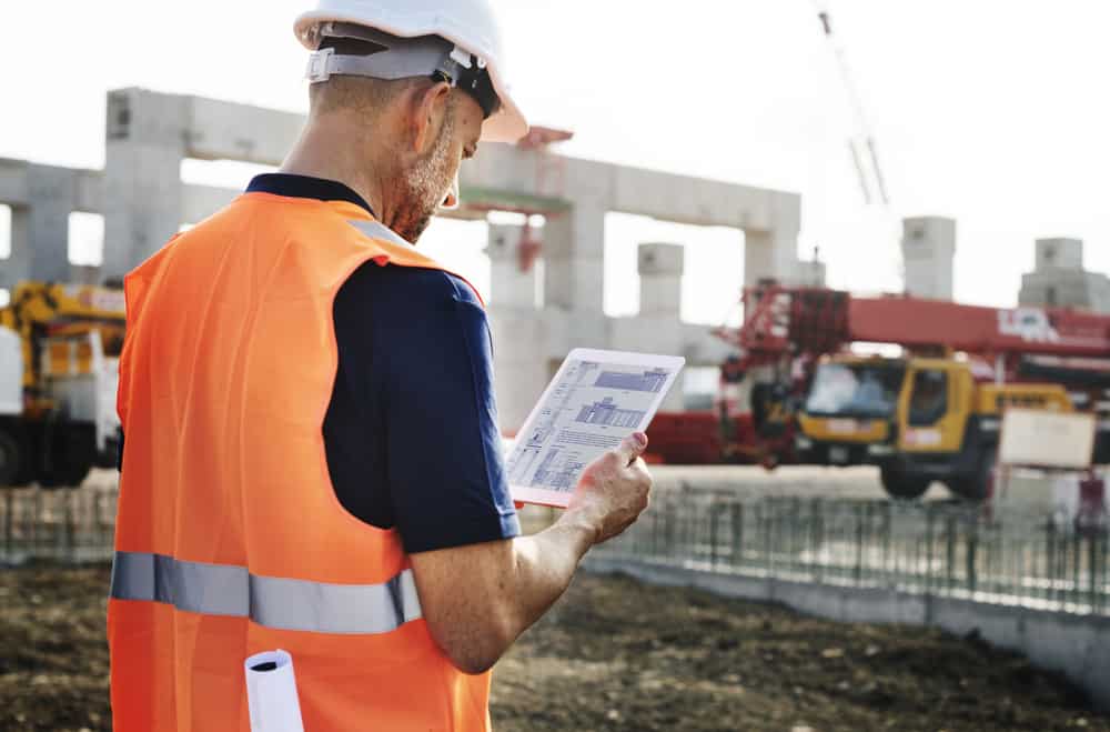 How to reduce labor cost in construction. Construction supervisor reading labor cost reports.