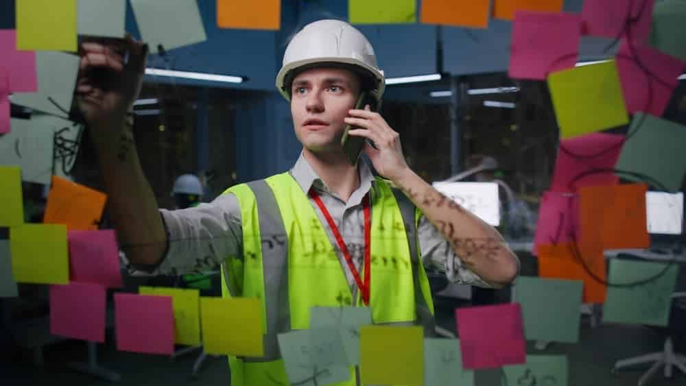What are the major construction scheduling problems facing your business? Construction worker writing on post-it notes attached to a board.